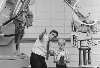 Man teaching kid to operate robotic tool