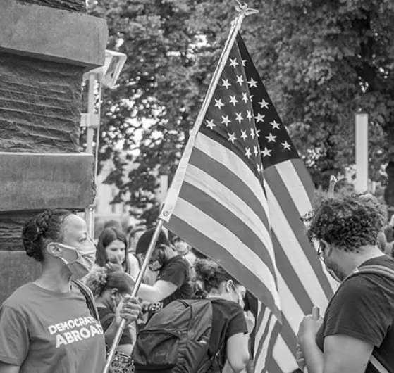 Black and white image of masked woman carrying an American flag