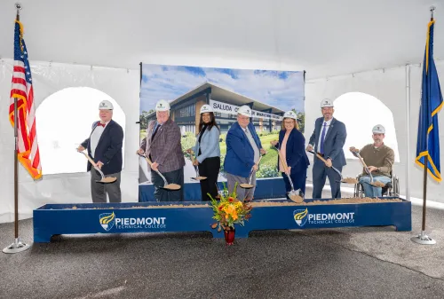 Administration posing in hard hats with shovels
